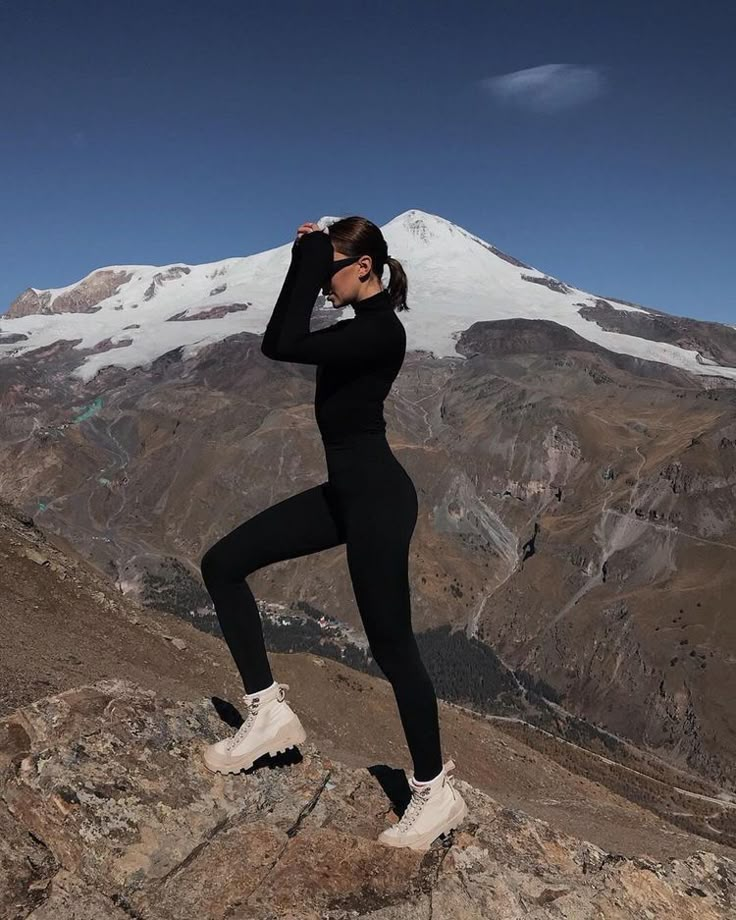 a woman standing on top of a rocky mountain