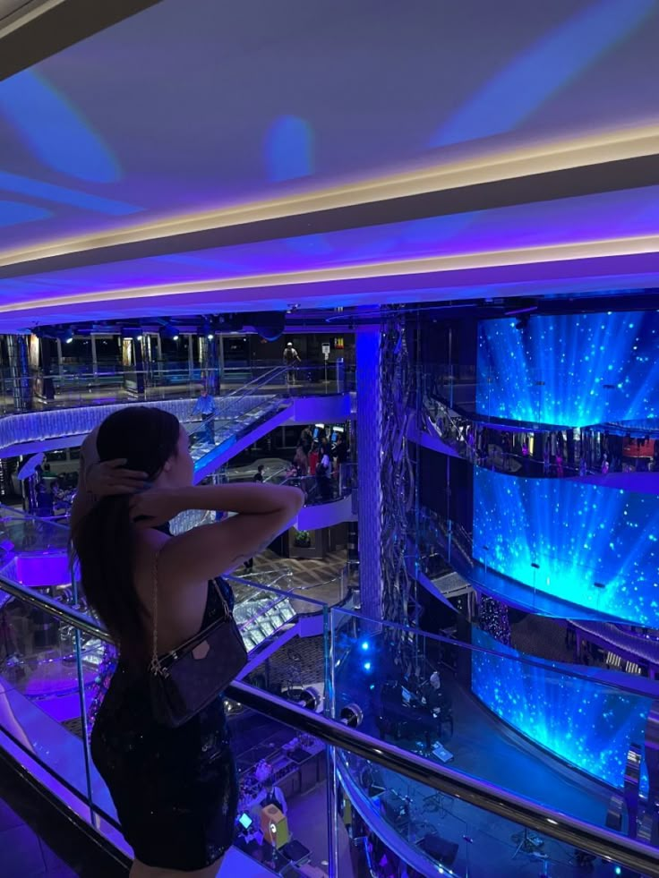 a woman standing on top of a balcony next to a blue and purple light display