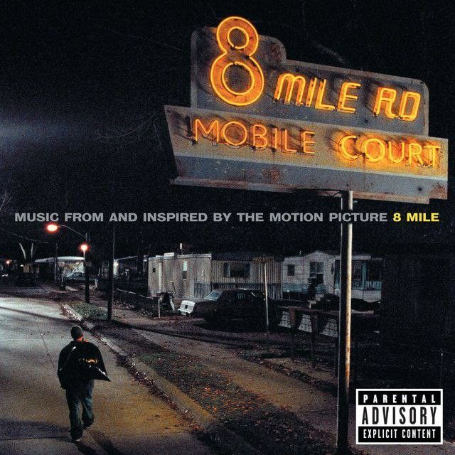 a man walking down the street in front of a sign that says 8 mile rd mobile court