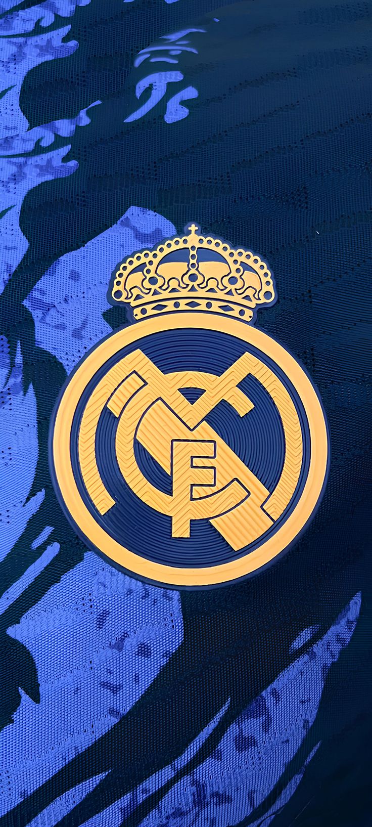 the real madrid crest is shown on a blue jersey with gold trims and a crown