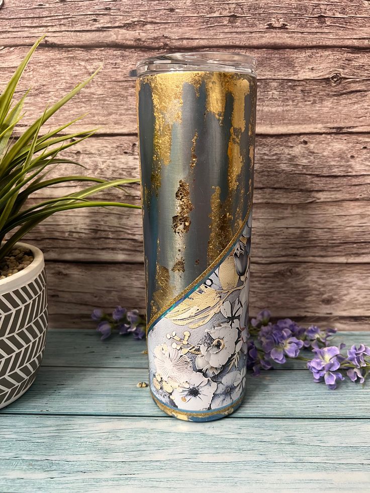 a vase sitting next to a potted plant on top of a wooden table