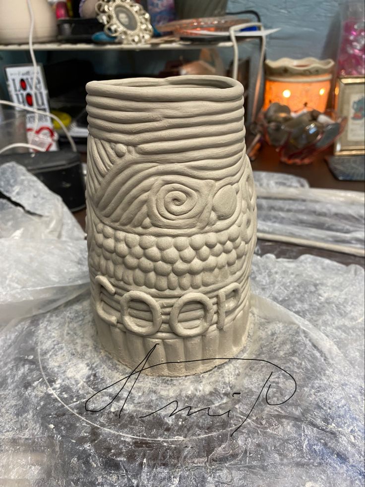 a white vase sitting on top of a table next to a glass container with an eye