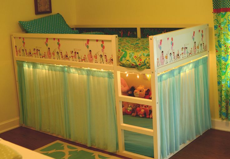 a child's bed with curtains and lights on the bottom bunk is decorated in green