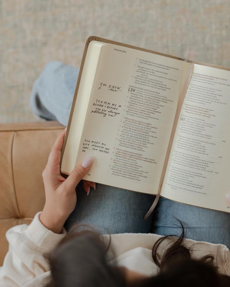 a person sitting on a couch holding an open book