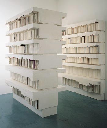 a large stack of books sitting on top of a blue floor next to a white wall