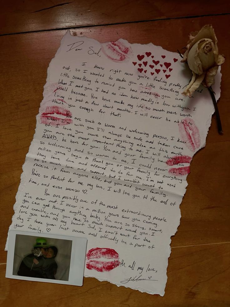 a piece of paper with writing on it next to a rose and a small photo