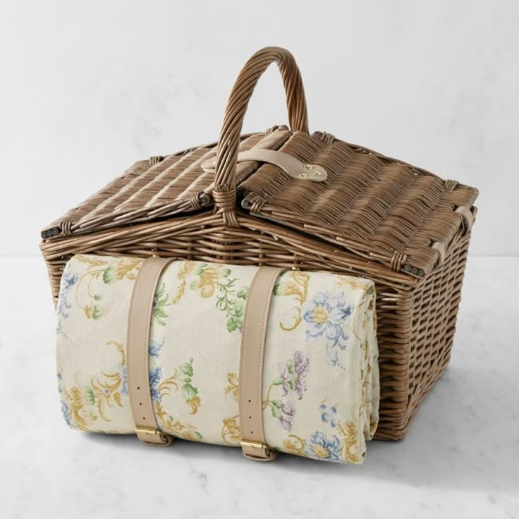 a wicker picnic basket with floral fabric linings and handles, sitting on a marble surface