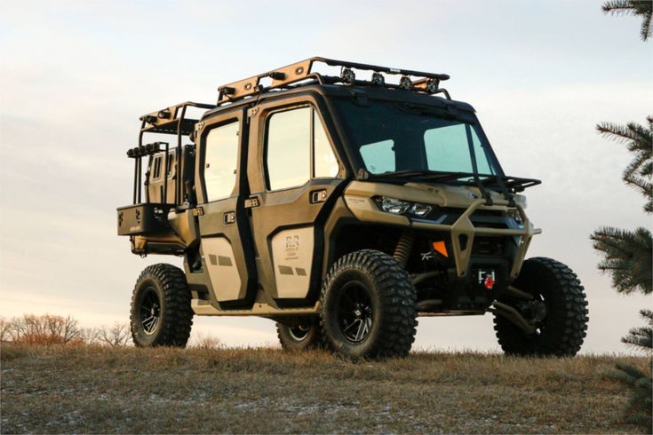 an off - road vehicle parked on top of a grass covered hill next to trees