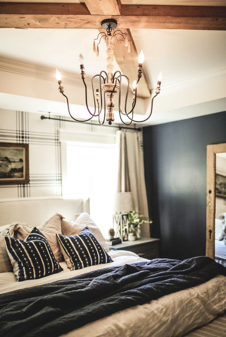 a bedroom with a chandelier hanging from the ceiling and pillows on the bed