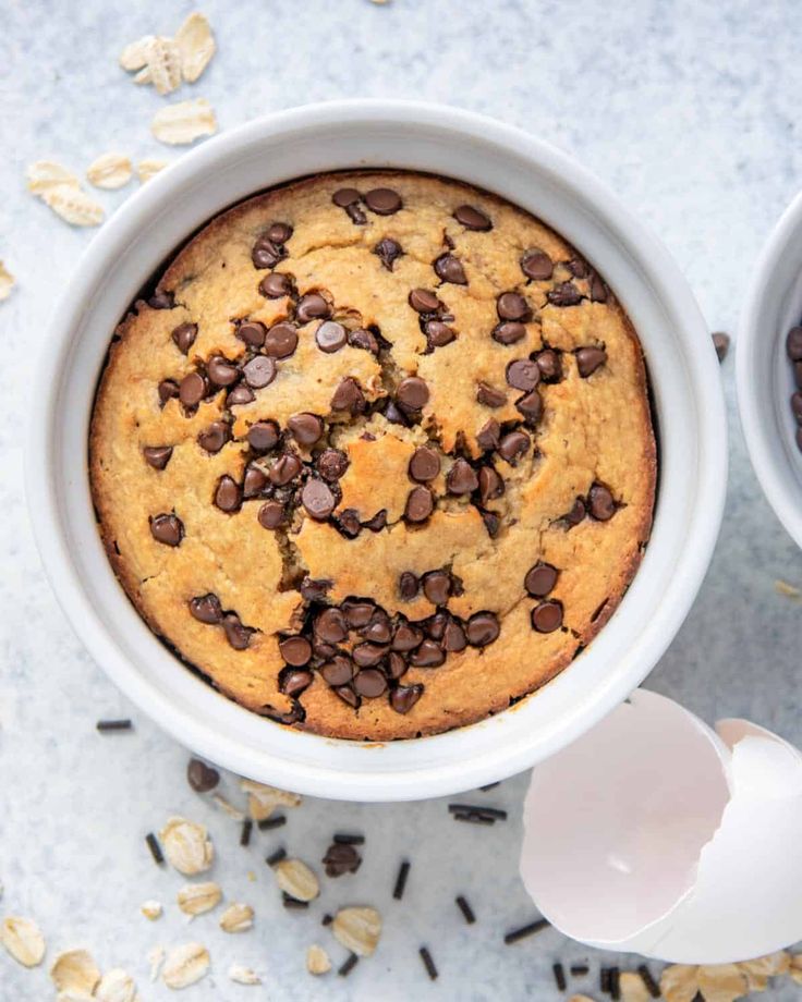 an overhead view of a baked dessert in a white bowl with chocolate chips on top