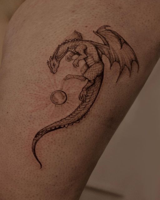 a small dragon tattoo on the right side of the leg, with an orb in it's mouth