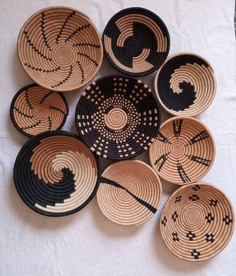 several black and white baskets are arranged on a tablecloth, one has an intricate design in the middle