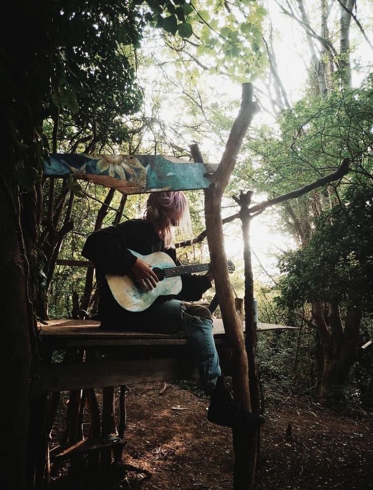 a person sitting on a bench playing an acoustic guitar