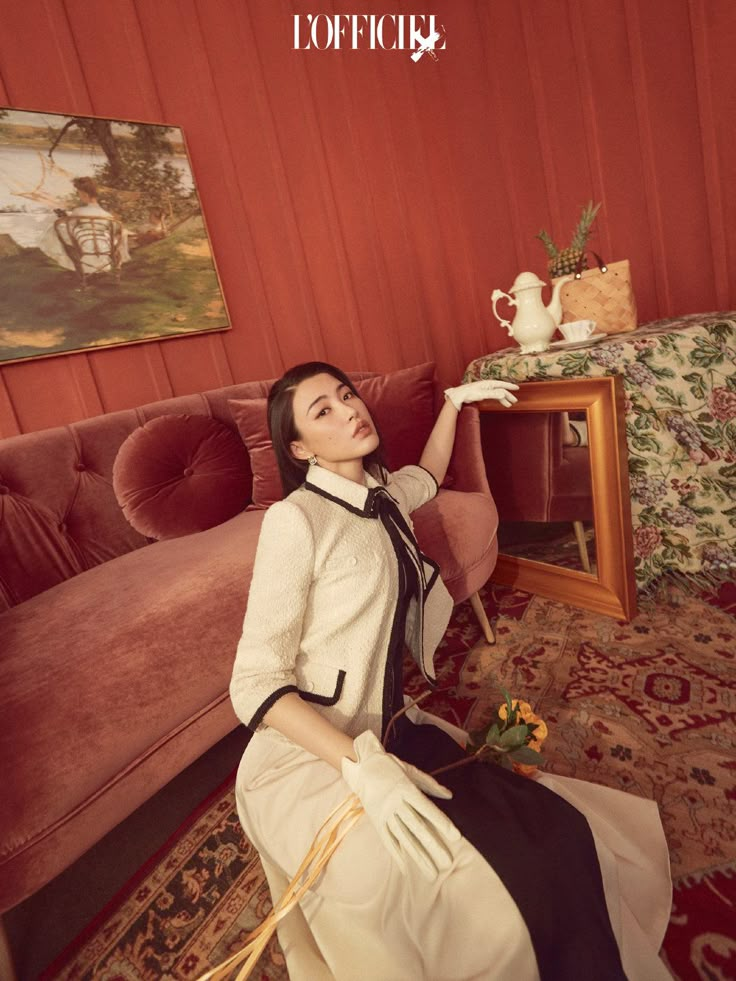 a woman sitting on the floor in front of a table with a vase and teapot