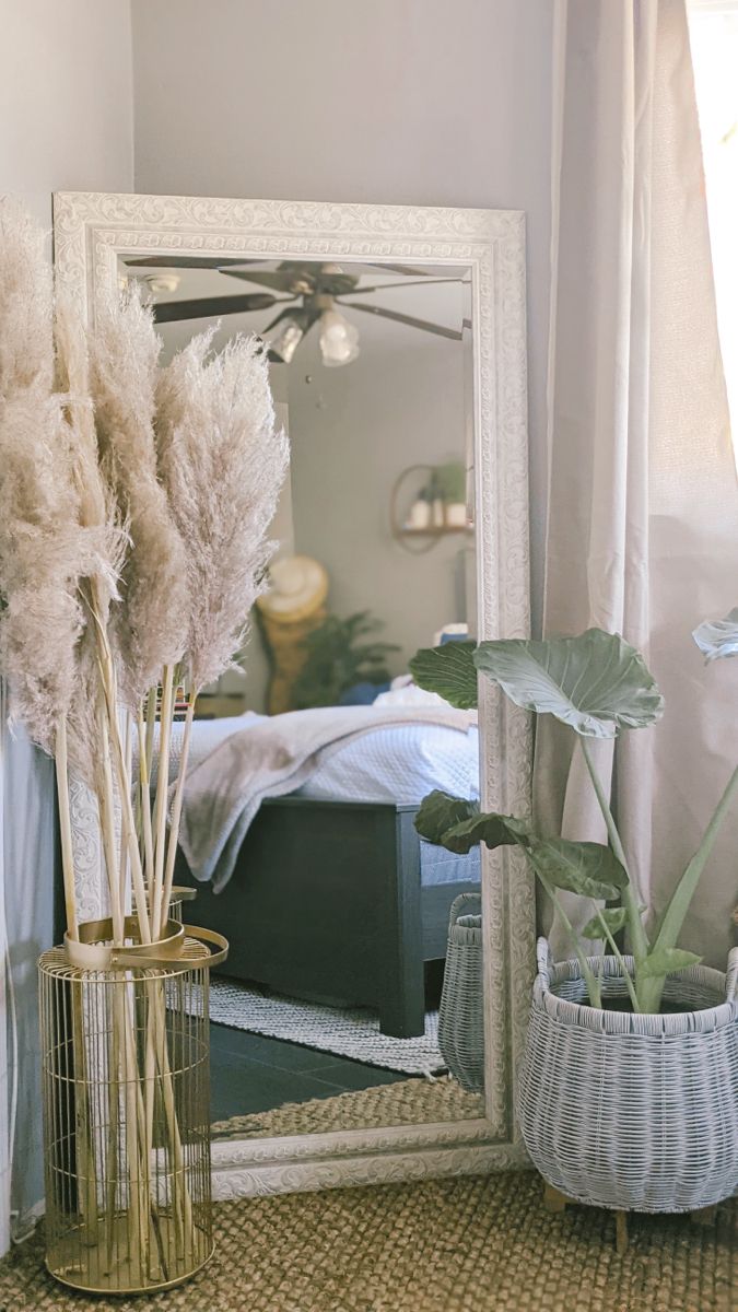 a mirror sitting on top of a table next to a vase with flowers in it