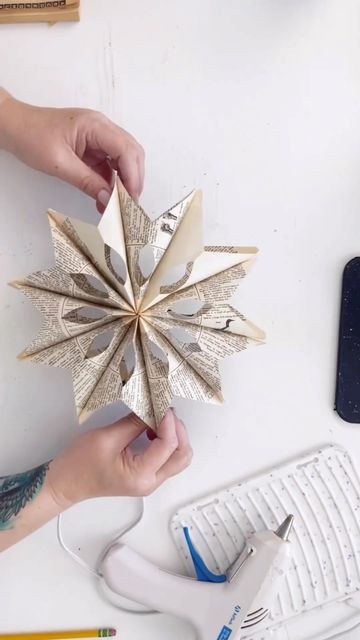 someone is holding a paper origami star in their left hand, while another person works on the computer