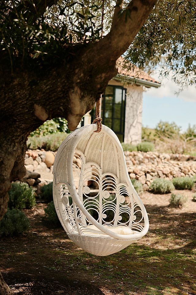 a white hanging chair next to a tree