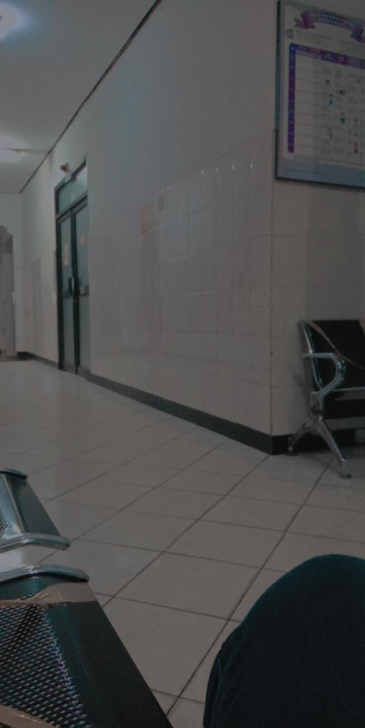 an empty hallway with chairs and luggage on the floor in front of it, next to a white tiled wall