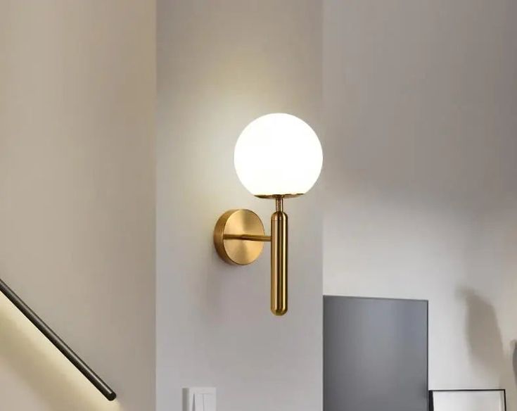 a light that is on the side of a wall next to a banister and stairs