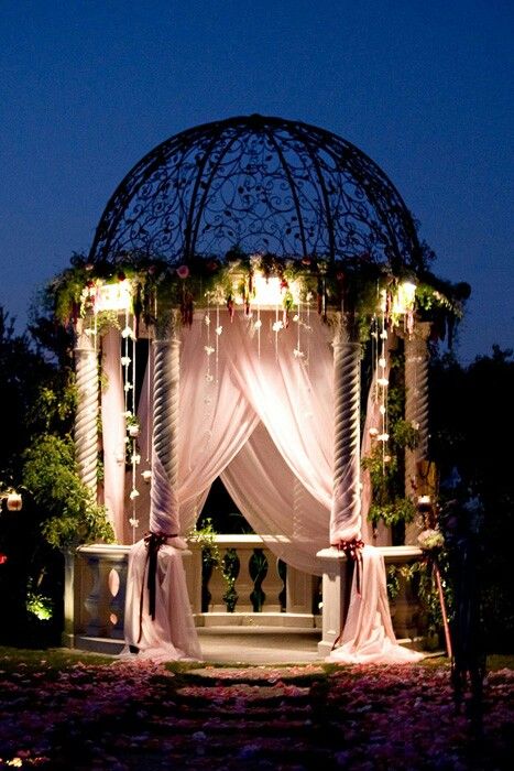 the gazebo is decorated with white drapes and lights