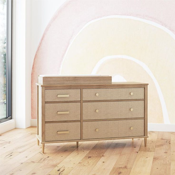 an empty dresser in front of a wall with a large painting on it's side