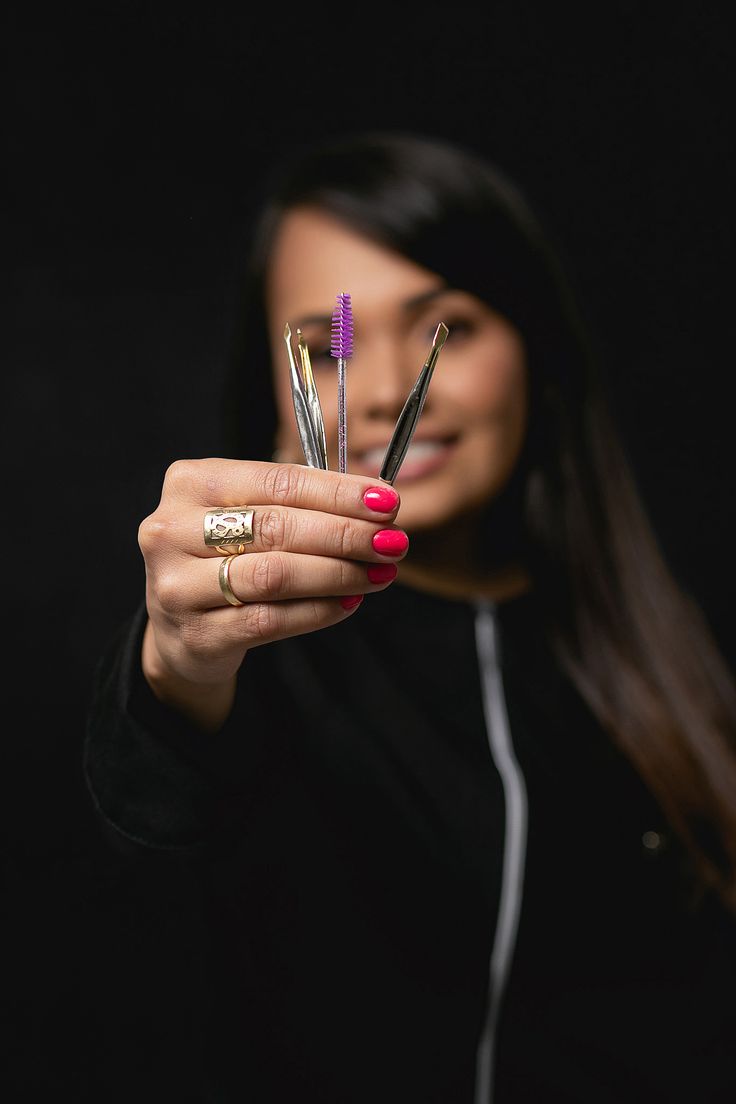 a woman holding up three different colored toothbrushes in one hand and two other