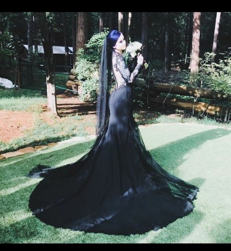 a woman in a long black dress holding flowers