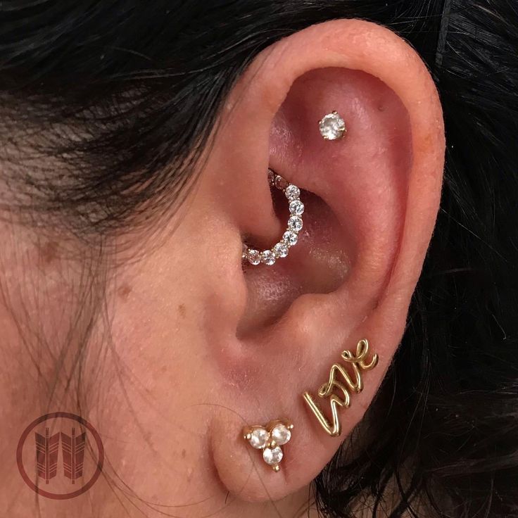 a woman wearing three different ear piercings with the word love written on each side