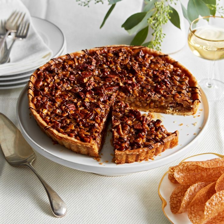 a pecan pie with one slice cut out on a plate next to some orange wedges