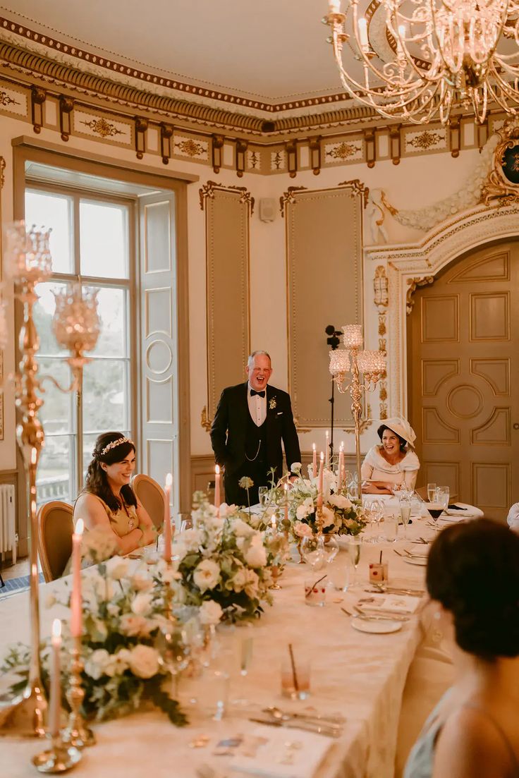 the bride and groom are standing at the head table in front of their wedding guests