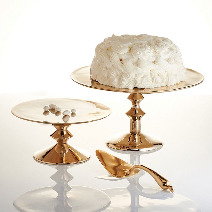 a white cake sitting on top of two gold pedestals next to eachother