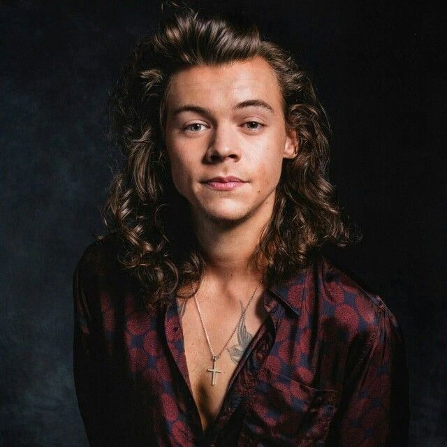 a young man with long hair wearing a red and black shirt posing for a photo