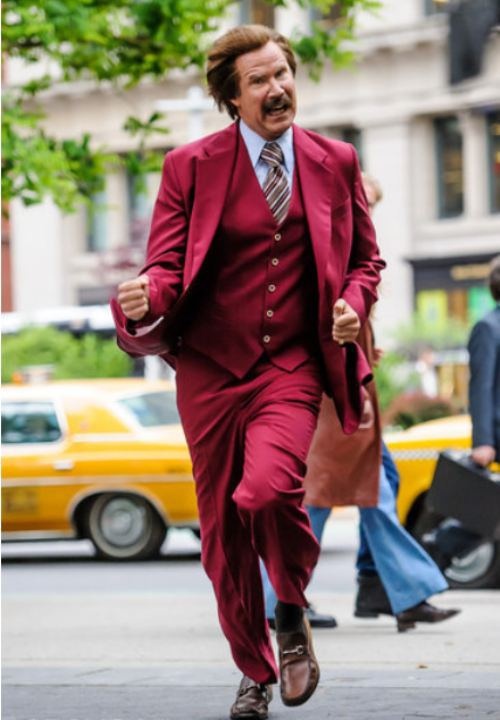 a man in a red suit and tie running down the street with his handbag