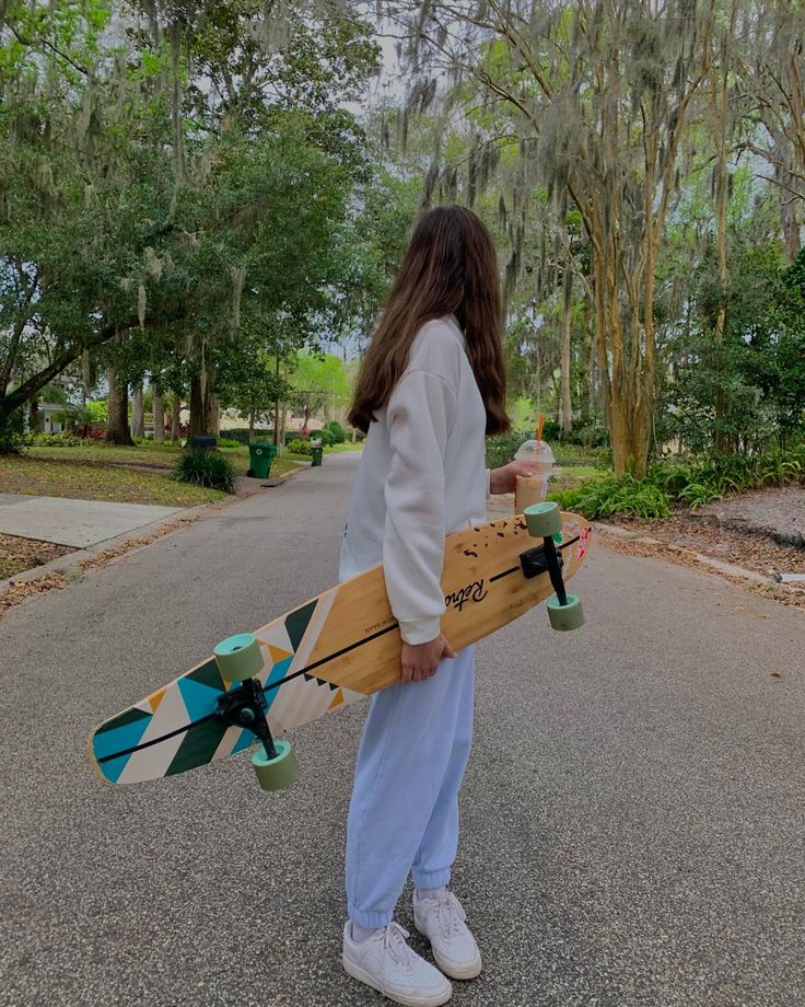 a person holding a skateboard and some trees