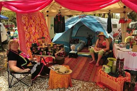 two women sitting in chairs under a tent with red drapes on the outside and inside