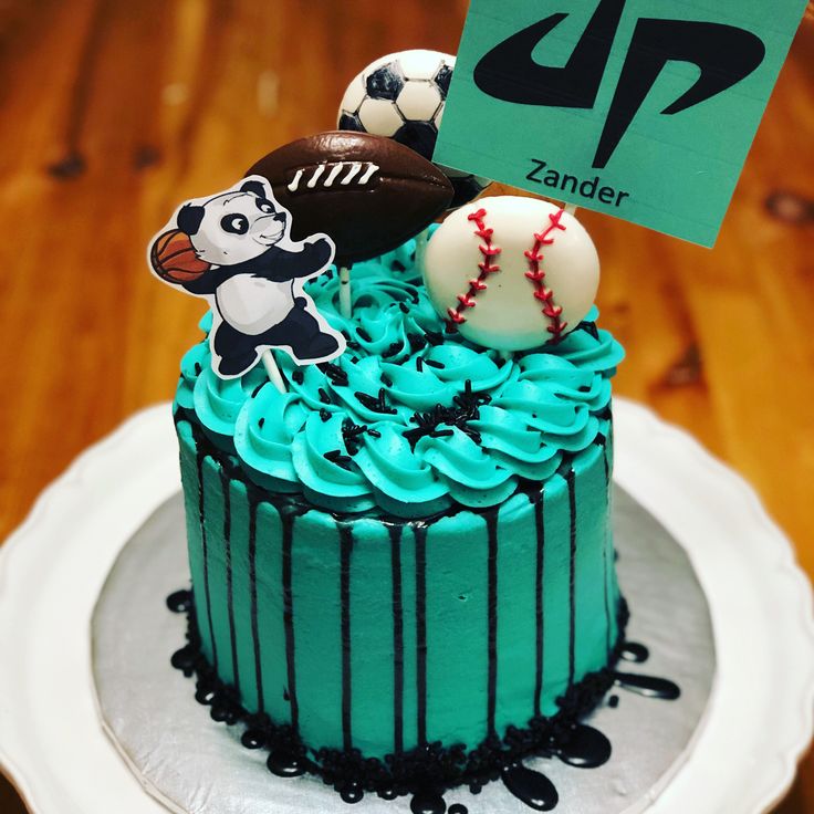 a cake decorated with blue icing and baseballs on top is displayed in front of a wooden table