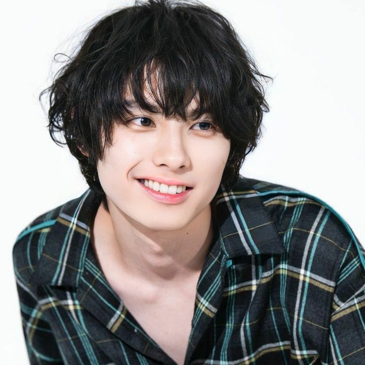 a young man with black hair wearing a plaid shirt