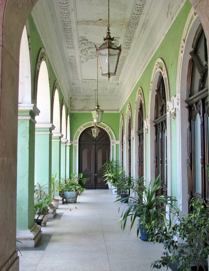 an arched hallway with potted plants on either side and two benches in the middle