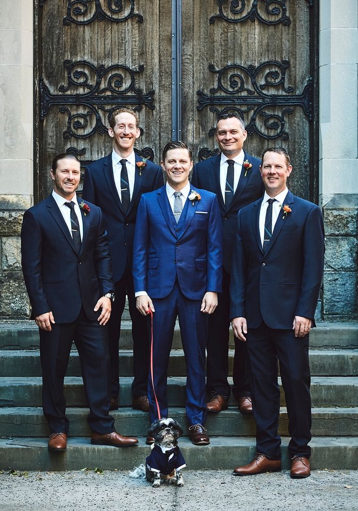 a group of men standing next to each other in front of a door with a dog on a leash