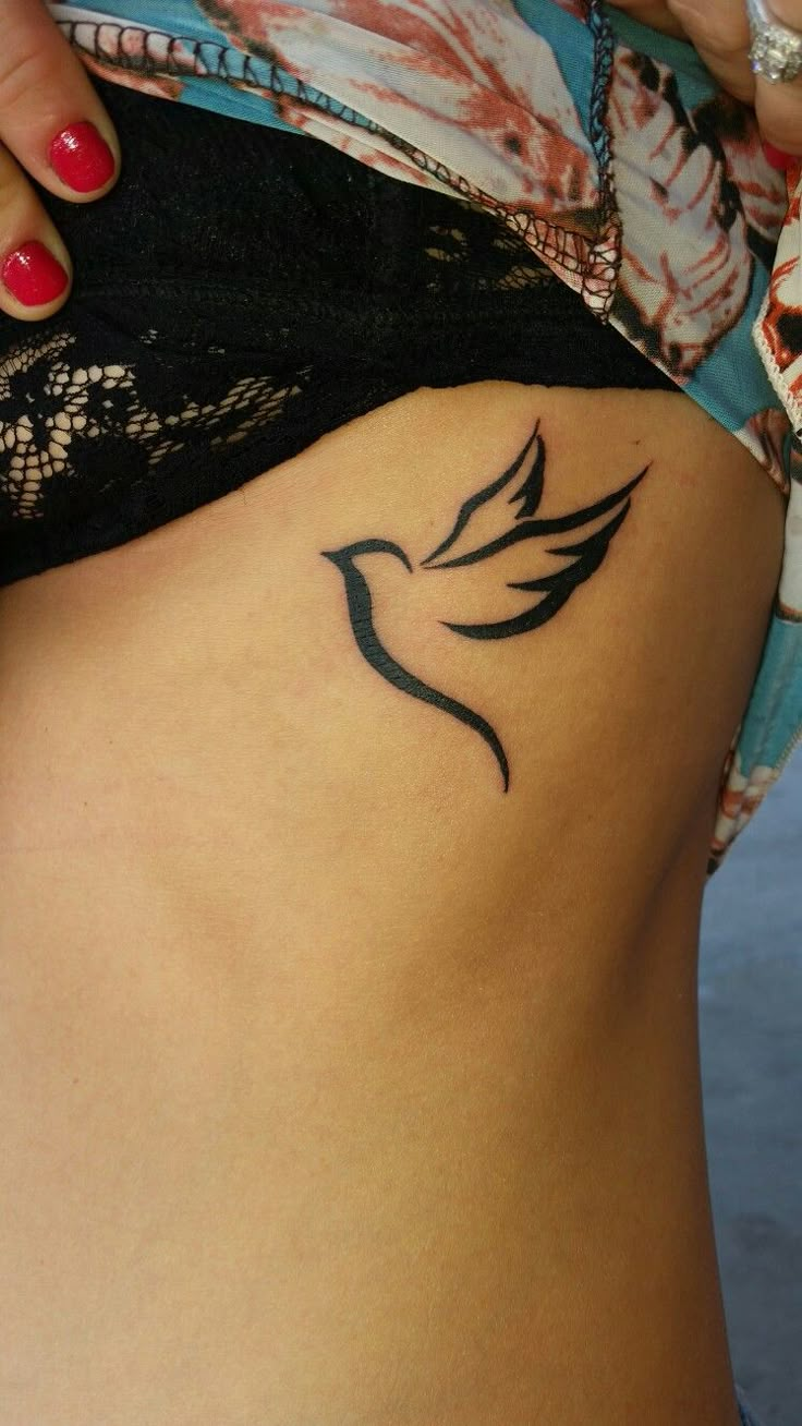 a woman's stomach with a bird tattoo on the side of her belly,