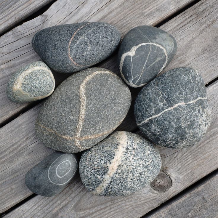 several rocks are arranged on a wooden surface, including one with a heart drawn on it