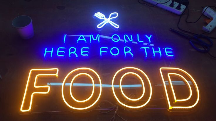 a neon sign that says i am only here for the food