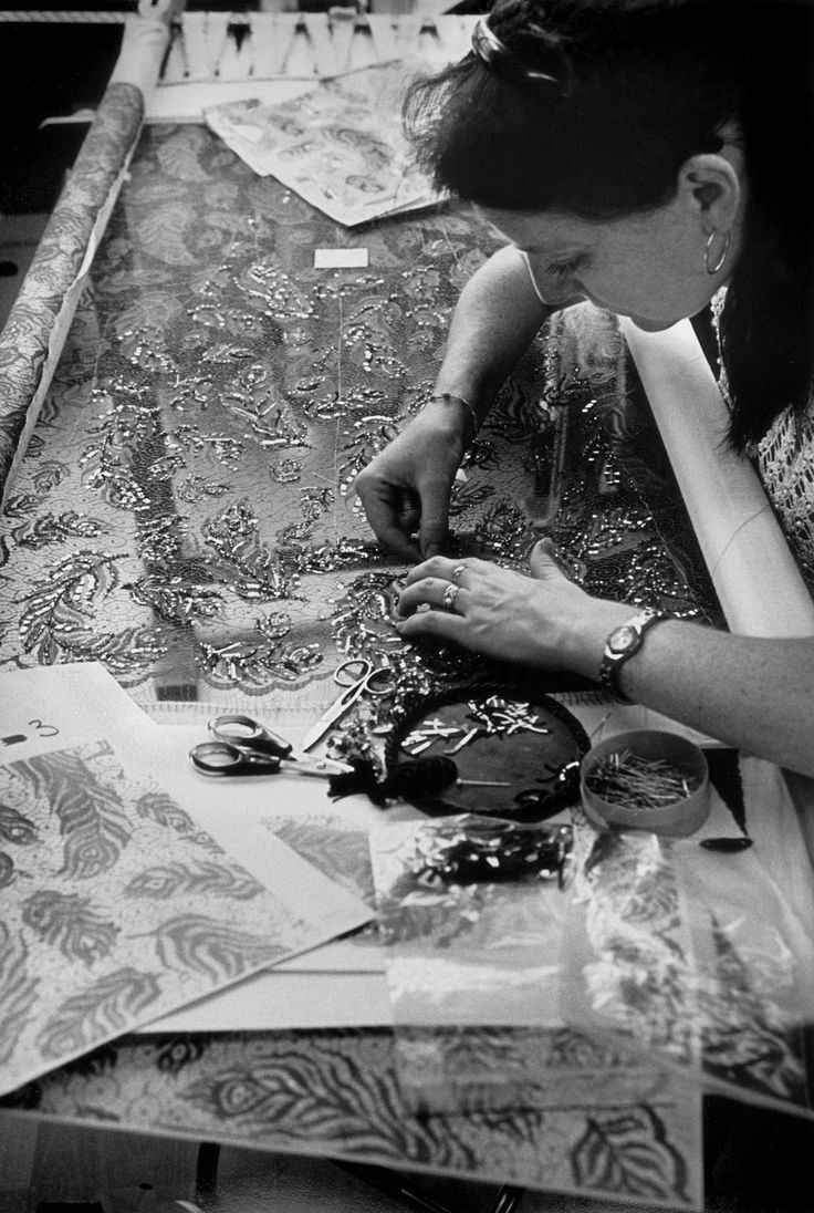 a woman sitting at a table working on fabric