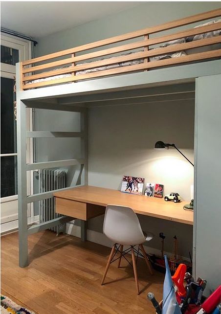 a loft bed with desk underneath it in a room next to a wall mounted radiator