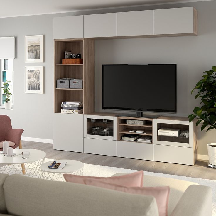 a living room with white furniture and a large flat screen tv mounted on the wall