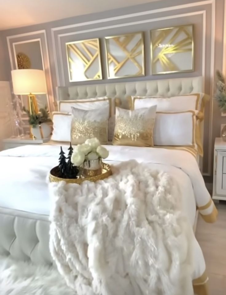 a bed with white and gold decor in a bedroom