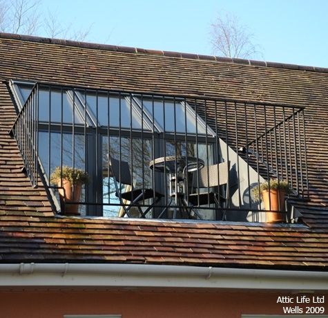 the roof of a building with many windows and plants in pots on top of it