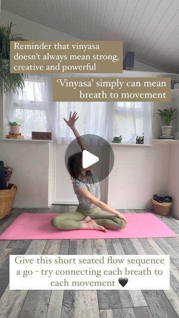 a woman sitting on a yoga mat with her arms in the air