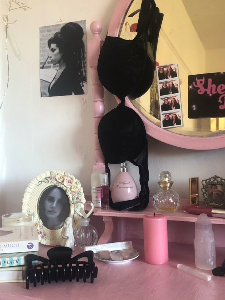 a pink dresser topped with lots of clutter and personal care items next to a mirror