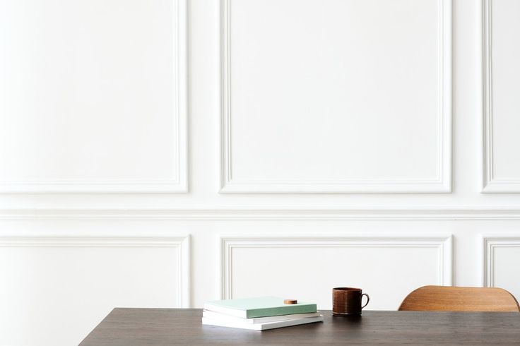 a wooden table with two books and a cup on it next to a white wall